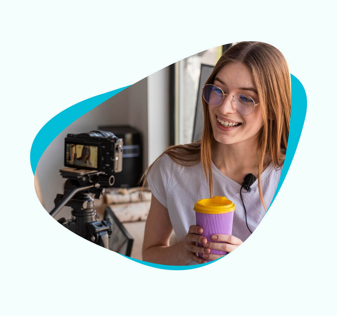 An influencer looking at her camera, holding a cup of coffee with both hands.
