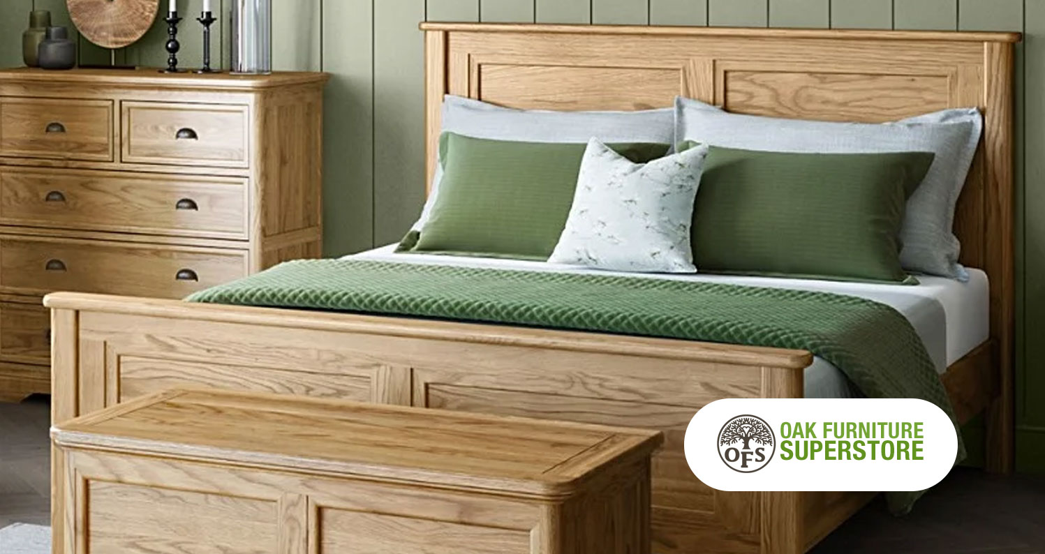 Wooden bed frame from Oak Furnutire Superstore with green and white sheets, pillows, and blankets.