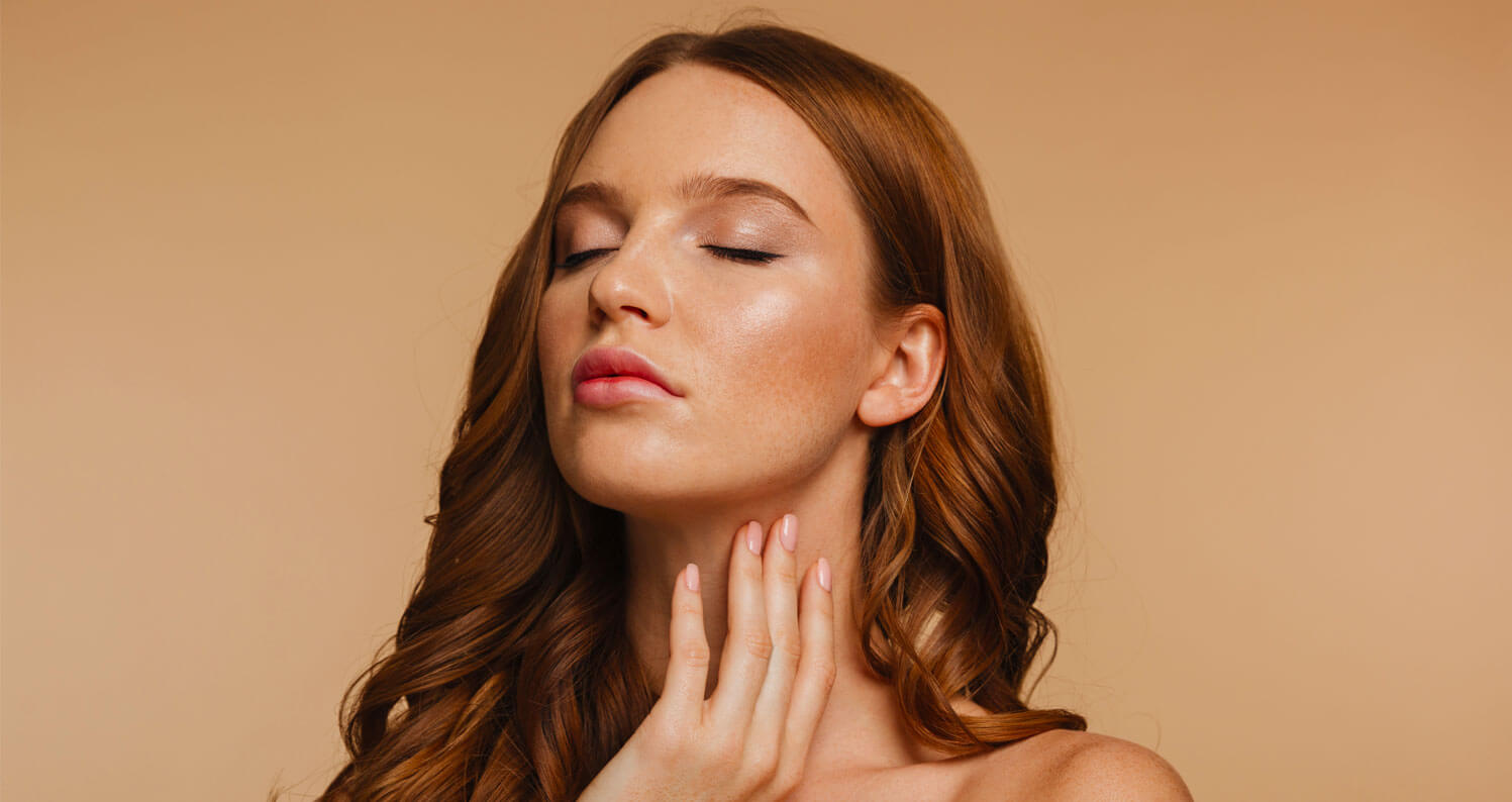 Woman applying skin care products to her face and neck.